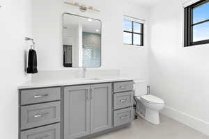 Bathroom featuring baseboards, toilet, and vanity