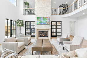 Living area with doors to music room, a towering ceiling,  fireplace, and hardwood floors