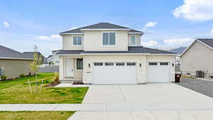 View of front of home featuring driveway, a garage, front lawn, and stucco siding