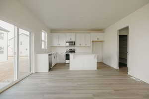 Kitchen with white cabinets, stainless steel appliances, a center island, and light wood-type flooring LARGE pantry