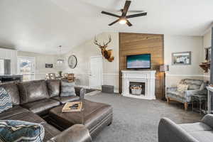 Carpeted living room with lofted ceiling, ceiling fan, and a fireplace