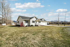 Ranch-style house featuring driveway, a garage, fence, and a front lawn