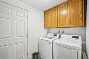 Clothes washing area featuring cabinet space and washing machine and dryer