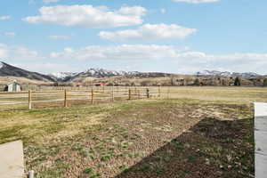 View of yard featuring fence, a rural view, and a mountain view
