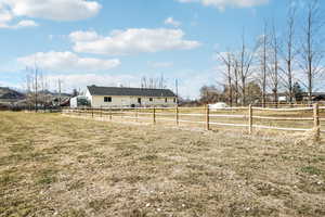 View of yard with an enclosed area, fence, and a rural view