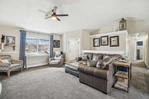 Living area featuring baseboards, ceiling fan, vaulted ceiling, and carpet