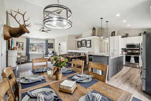 Dining room featuring recessed lighting, ceiling fan with notable chandelier, vaulted ceiling, and light wood-type flooring