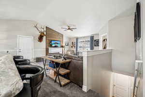 Carpeted living area with lofted ceiling, a fireplace, and a ceiling fan