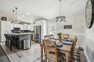 Dining room with light wood-style flooring, baseboards, vaulted ceiling, and recessed lighting