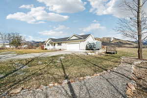 View of front facade with driveway, an attached garage, a mountain view, and a front lawn