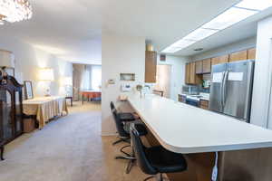 Kitchen featuring freestanding refrigerator, light countertops, white range with electric stovetop, and light carpet