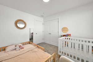 Carpeted bedroom featuring a closet and visible vents