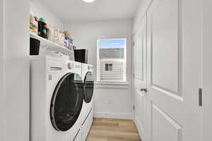 Clothes washing area featuring light wood-style flooring, independent washer and dryer, baseboards, and laundry area