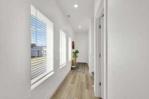Hallway featuring baseboards, visible vents, light wood-style flooring, and recessed lighting