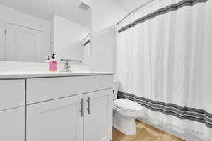 Full bathroom with visible vents, wood finished floors, toilet, and vanity