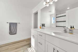 Bathroom featuring a sink, baseboards, visible vents, and wood finished floors