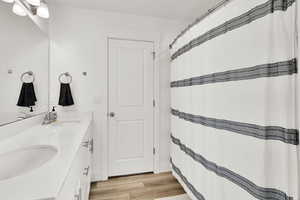 Bathroom featuring double vanity, wood finished floors, and a sink