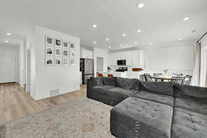 Living area featuring recessed lighting, baseboards, a textured ceiling, light wood-style floors, and visible vents