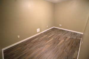 Spare room featuring baseboards and dark wood finished floors