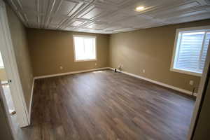 Unfurnished room with baseboards and dark wood-type flooring