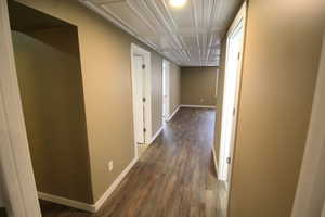 Hall with baseboards and dark wood-type flooring