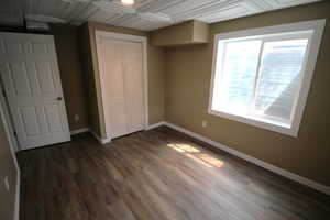 Unfurnished bedroom with baseboards, dark wood-style flooring, and a closet