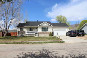 Ranch-style house featuring a porch, a front yard, concrete driveway, an attached garage, and fence