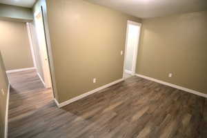 Spare room with baseboards and dark wood-type flooring