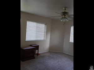 Carpeted spare room with baseboards and a ceiling fan