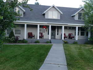 View of front of property featuring a front lawn, a porch, and roof with shingles