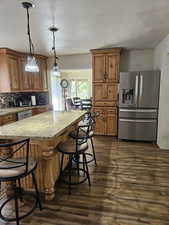 Kitchen featuring a kitchen bar, tasteful backsplash, stainless steel appliances, dark wood finished floors, and brown cabinets