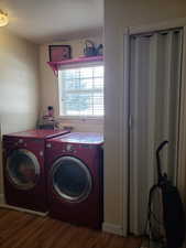 Clothes washing area with washing machine and dryer, wood finished floors, and laundry area