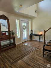 Entryway with a textured ceiling, wood finished floors, baseboards, and stairs