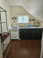 Kitchen with a sink, dark cabinetry, white range with gas cooktop, lofted ceiling, and dark wood-style flooring