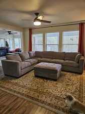 Living area featuring a fireplace, wood finished floors, and ceiling fan