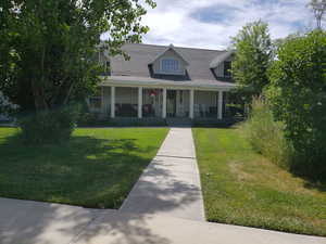 New england style home featuring a front lawn and a porch