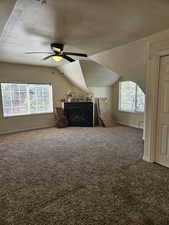 Additional living space with a textured ceiling, baseboards, a ceiling fan, carpet floors, and vaulted ceiling