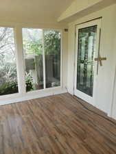 Unfurnished sunroom featuring a textured ceiling and wood finished floors