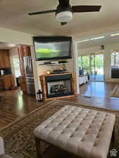 Living area featuring dark wood-type flooring, visible vents, a ceiling fan, and a fireplace