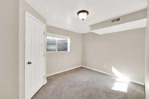 Spare room with baseboards, carpet floors, a textured ceiling, and visible vents