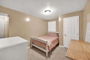 Bedroom featuring baseboards, a textured ceiling, and light carpet