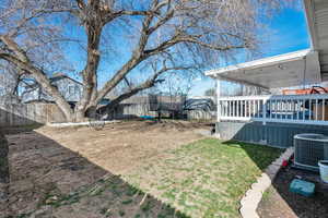 View of yard featuring a fenced backyard, central AC, and a deck