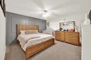 Bedroom with a ceiling fan, a decorative wall, and light colored carpet