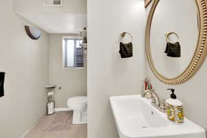 Bathroom featuring visible vents, baseboards, toilet, a sink, and tile patterned flooring