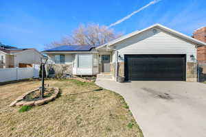 Ranch-style house featuring fence, an attached garage, driveway, a front yard, and solar panels