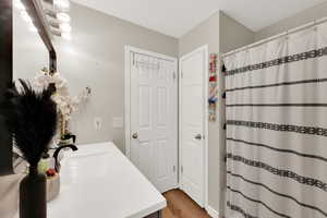 Bathroom with vanity, curtained shower, and wood finished floors