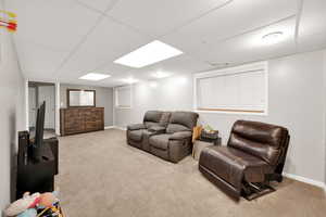 Carpeted living room featuring baseboards and a drop ceiling