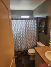 Full bathroom with vanity, wood finished floors, a textured ceiling, curtained shower, and toilet