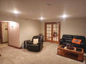 Carpeted living room with arched walkways, french doors, and baseboards