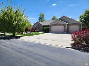 Single story home featuring an attached garage, brick siding, driveway, and stucco siding